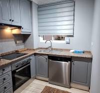 A kitchen in a 3-room apartment with a gray kitchen unit and stainless steel appliances.