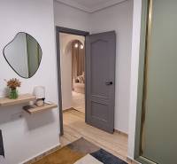 A hallway of a 3-room apartment with shelves, a mirror, and open doors.