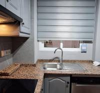 A kitchen in a 3-room apartment with a granite countertop and gray cabinets.