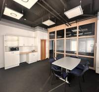 Office with a desk and chairs, kitchenette, and glass partition.