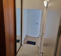 Entrance hallway in a 2-room apartment with tiles, a wardrobe, and white doors.