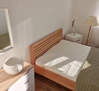 A bright bedroom with a wooden bed and a lamp in a two-room apartment.