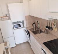 Kitchen in a 2-room apartment with a white kitchen unit, appliances, and a sink.