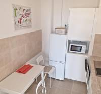 Dining room in a 2-room apartment with white furniture and kitchen appliances.
