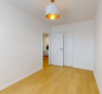 An empty room with wooden flooring and a pendant light in a 3-room apartment.