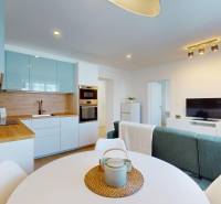 Kitchen and living room in a 3-room apartment with wooden paneling and white appliances.