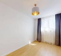 An empty room in a 3-room apartment with a parquet floor and curtains on the window.