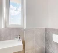 Bathroom from a 3-room apartment with a sink, window, and gray tiles.