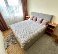 Bedroom with a bed, pillows, and nightstands in a three-room apartment.