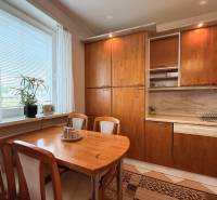Kitchen in a 3-room apartment with a table, chairs, cabinets, and a dishwasher.