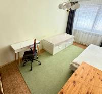 A room with two beds, a desk, and a chair in a 3-room apartment.