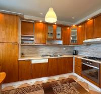 A kitchen in a 3-room apartment with wooden cabinets and a marble countertop.