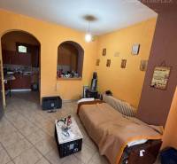 Living room in a family house with a bed, a small table, and arched doors.
