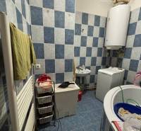 A bathroom with blue tiles and a washing machine in a family house, storage baskets for laundry.