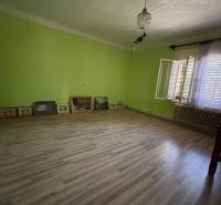 A room in a family house with a floating floor, green walls, and a large window.
