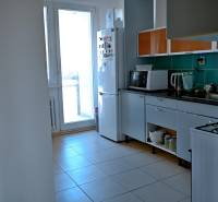 A kitchen with appliances and cabinets in a 3-room apartment with a balcony.