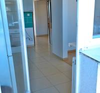 A view into the hallway of a 3-room apartment with tiles and a kitchen view.