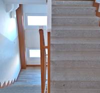 A staircase in a 3-room apartment with wooden railing and windows for natural light.