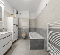 Bathroom with a sink, bathtub, toilet, and ladder radiator in a 2-room apartment.