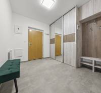 Entrance hallway with wooden furniture and a green bench in a 2-room apartment.