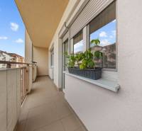 The balcony of a 2-room apartment on Dona Sandtnera Street in the town of Pezinok, with flowers on the windowsill.