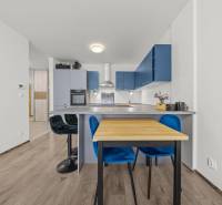 A kitchen in a 2-room apartment with blue cabinets, a dining table, and bar stools.