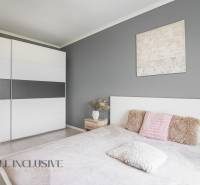 A bedroom in a 2-room apartment with a gray wall, a wardrobe, and decorative pillows.