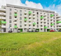 A building with colorful balconies, a parking lot, and greenery in Galanta near Sereď Street.