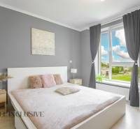 A bright bedroom in a 2-room apartment with a large window and subtle decoration.