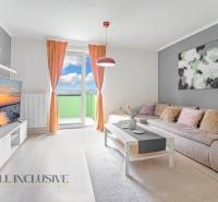 Living room of a two-room apartment with a sofa, television, and balcony, light curtains and accessories.