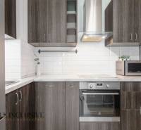 Kitchen in a 2-room apartment with appliances and wooden cabinets, white tiles.
