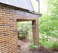 A cottage in Kokava nad Rimavicou with a brick facade amidst a forest scenery.