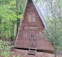 A wooden cabin in the forest near Kokava nad Rimavicou with a triangular roof and a peaceful surroundings.