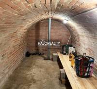 A brick cellar in a cottage with a wooden table and stored bottles.