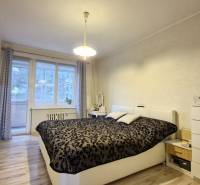 Bedroom in a 3-room apartment with a bed, a TV on the wall, and balcony doors.