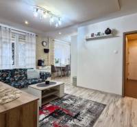Living room in a 3-room apartment with a comfortable sofa, modern curtains, and a dining table.