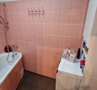 Bathroom with a bathtub and a washing machine, beige tiles, part of a 3-room apartment.