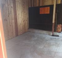 Wooden interior of a cabin with a concrete floor and wooden walls.