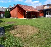 A cottage in Tužina with a wooden extension and a green yard.