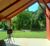 Covered terrace at the cottage in Tužina with a view of the green lawn and trees.