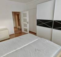 Bedroom in a 2-room apartment with a bed, wardrobe, and dresser, light wooden floors.