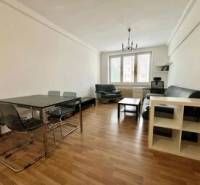 Living room in a two-room apartment with a dining table and a sofa on a wooden floor.