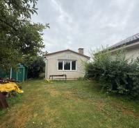 A garden at a family house in Ludanice with a lawn, trees, and a metal shelter.