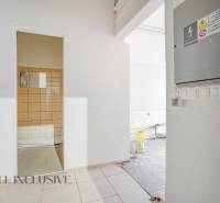 Unfinished commercial spaces with visible electrical installations, white and brown tiles.