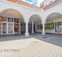 Commercial spaces in Dunajská Streda with arched arcades and advertising for discounts.