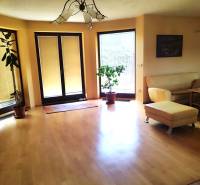 Living room in a family house with wooden flooring, a sofa, and plants.