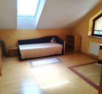 Attic room with a bed, wardrobe, and table in a family house.