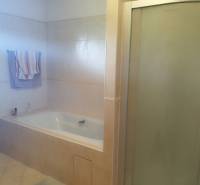 A bathroom in a family house with a bathtub and a shower, tiles in beige tones.