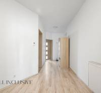 A hallway in a family house with wooden flooring and light-colored furniture.