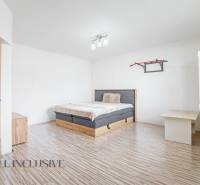 Bright bedroom in a family house with wooden flooring and a bed.